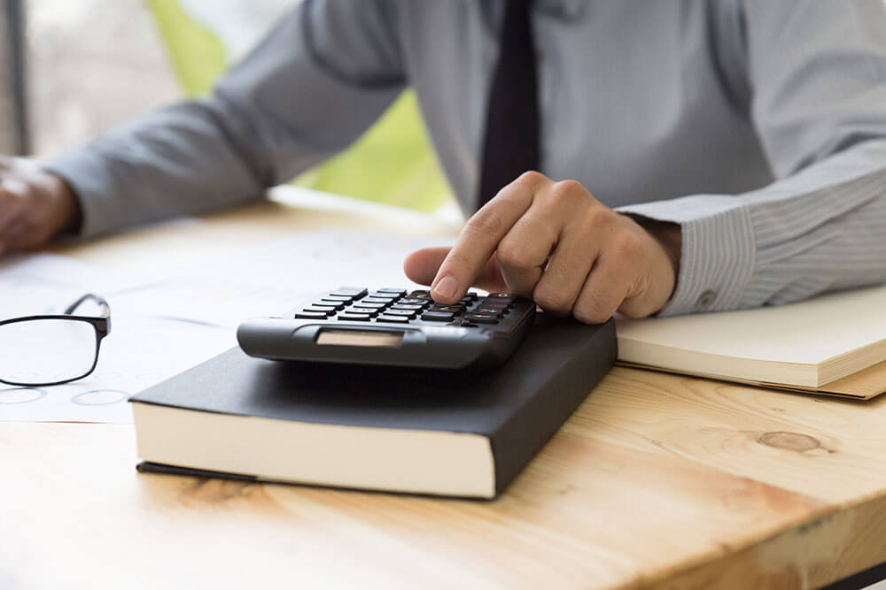 Businessman analyzing report on chart with calculator facility manager calculating